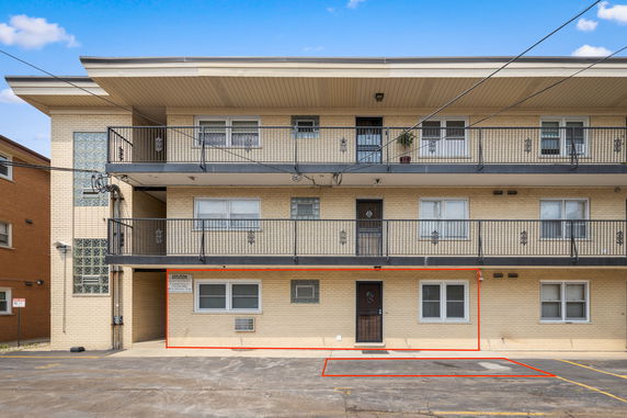 Front view of a multi-story apartment building with a beige brick exterior and balconies.