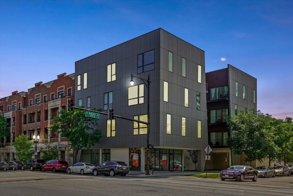 Front view of a modern multi-story building on a street corner.