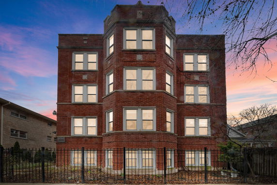 Front view of a multi-story brick building with a fenced exterior.