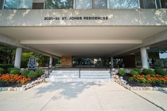 Front view of a residential building with stairs and a canopy entrance.