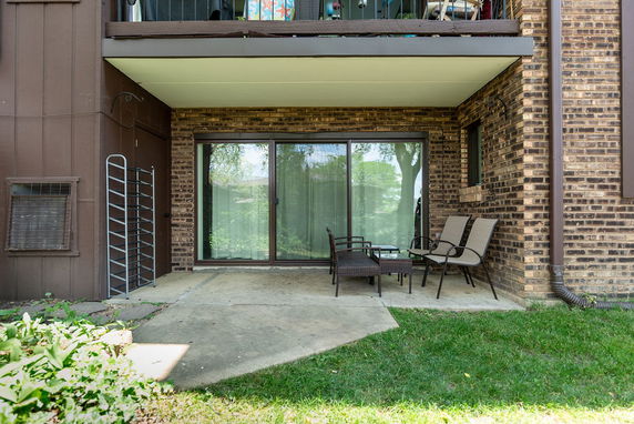 Front view of a ground-level patio with a brick exterior and sliding glass doors.