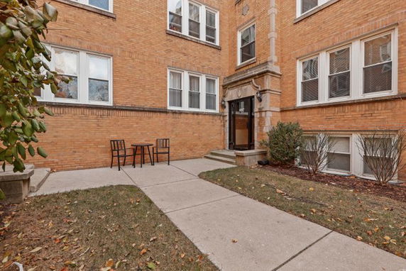 Front view of a multi-story brick building with a small outdoor seating area.