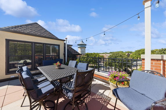 Rooftop patio with seating area and view of surrounding buildings and trees.