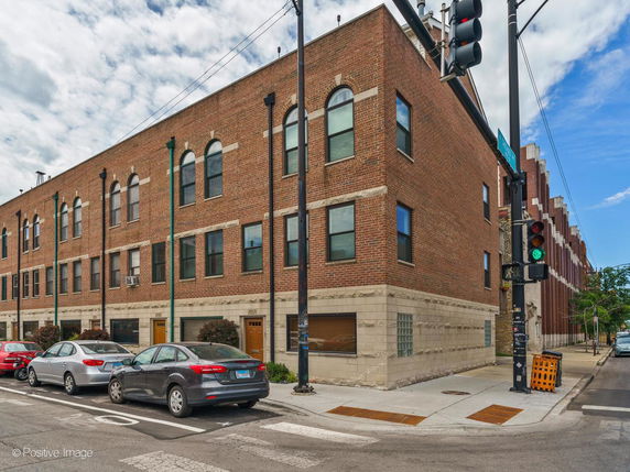 Front view of a multi-story brick building at a street corner.