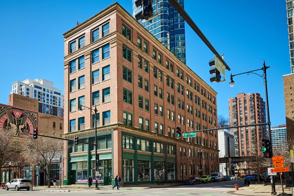 Front view of a multi-story brick building on a street corner.