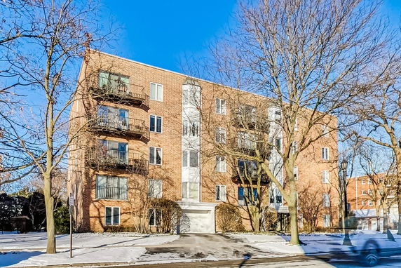 Front view of a multi-story brick apartment building with balconies.