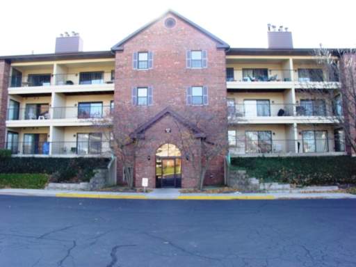 Front view of a multi-story brick apartment building with balconies.