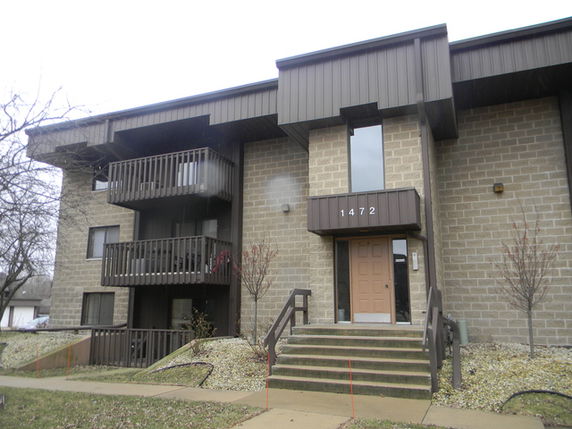 Front view of a multi-story building with balconies and brick facade.