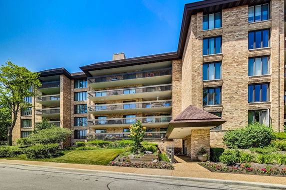 Front view of a multi-story apartment building with balconies and brick facade.