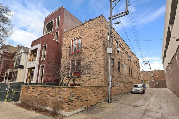 Front view of a multi-story building with brick exterior and parking area.