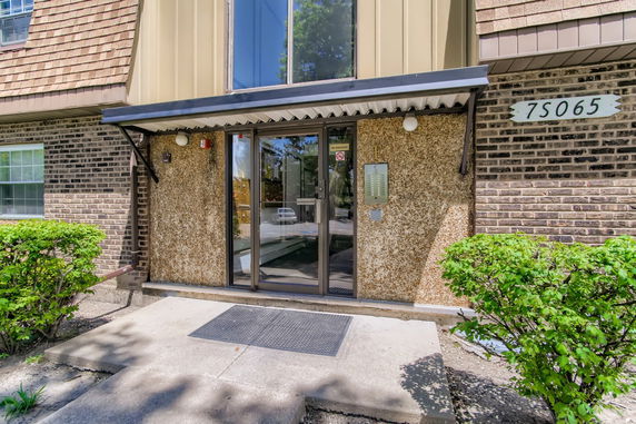 Front view of a two-story building entrance with a glass door and brick exterior.
