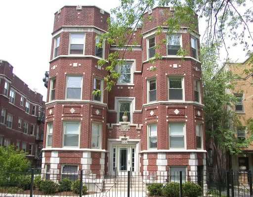 Front view of a multi-story brick apartment building with symmetrical design and decorative elements.