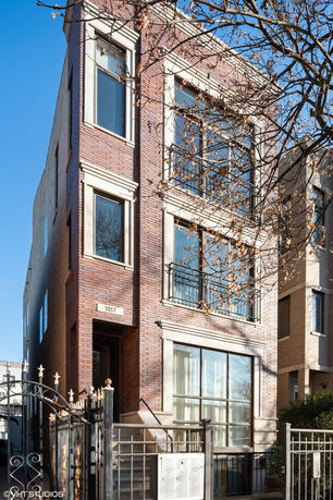 Front view of a multi-story brick building with large windows and a gated entrance.