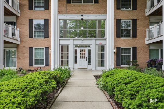 Front view of a multi-story brick building with a central entrance and balconies.
