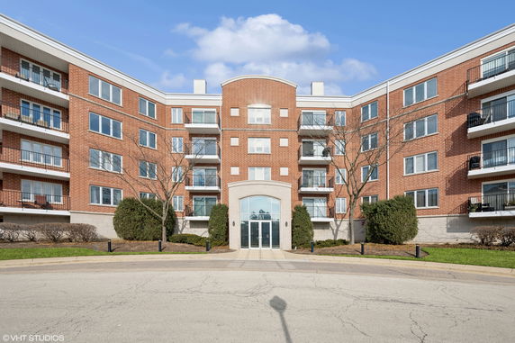 Front view of a multi-story brick apartment building with balconies.