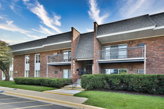 Front view of a brick residential building with two levels and balconies.