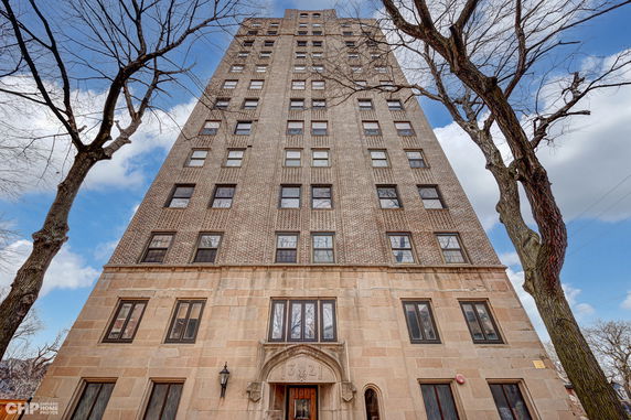 Front view of a tall brick and stone apartment building.