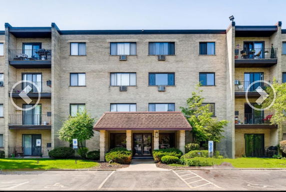 Front view of a multi-story apartment building with a covered entrance.