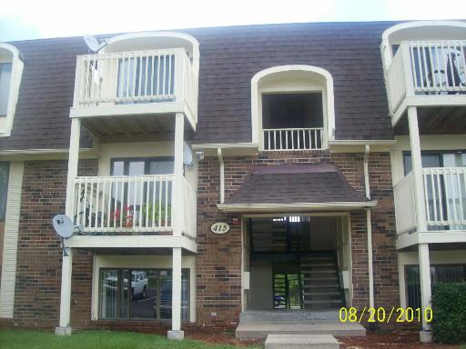 Front view of a multi-story brick apartment building with balconies.