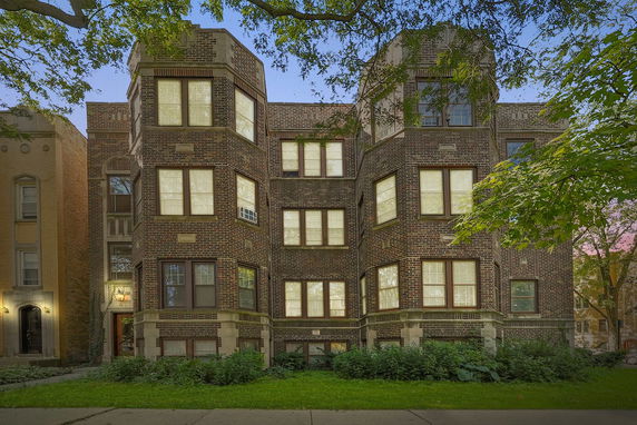 Front view of a multi-story brick apartment building with large windows.