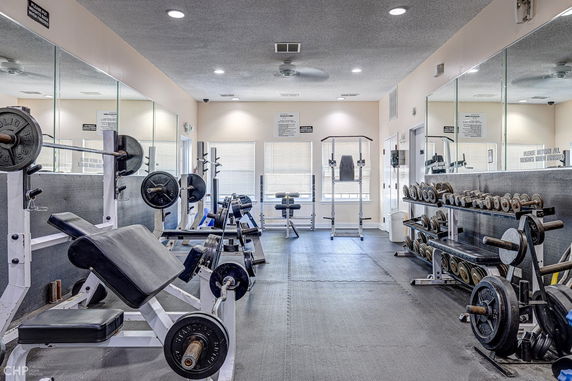 Interior view of a gym with weightlifting equipment and mirrors.
