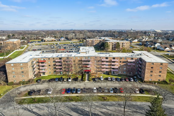 Front view of a multi-story apartment building with parking area.