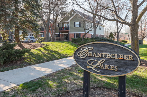 Front view of a two-story residential building with a small sign in the foreground.