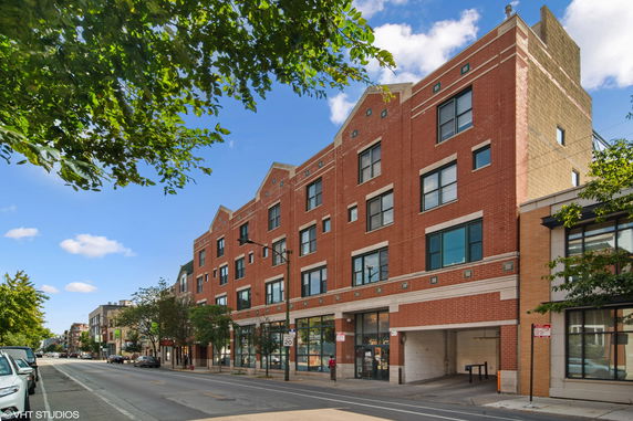 Street view of a multi-story brick building with large windows and an entrance.