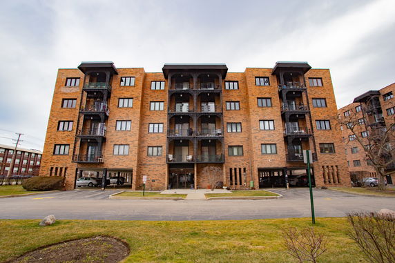 Front view of a multi-story brick apartment building with balconies.