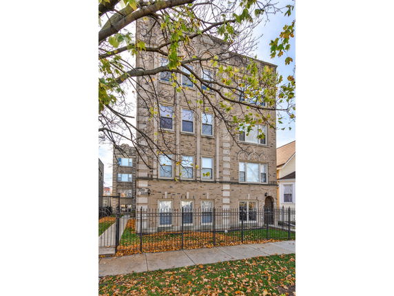 Front view of a multi-story brick building with several windows and a gated entrance.