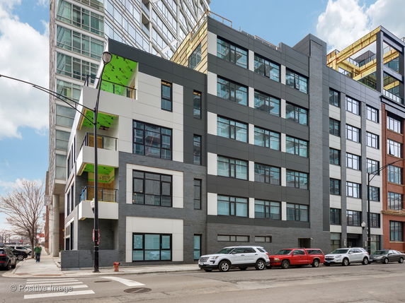 Front view of a modern multi-story building with large windows and a mixed material facade.