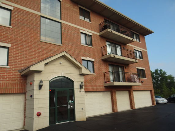 Front view of a multi-story apartment building with balconies and garage doors.