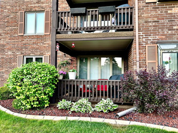 Front view of a brick building with balconies and a small garden area.