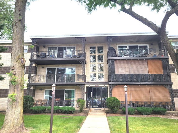 Front view of a three-story apartment building with balconies and large windows.