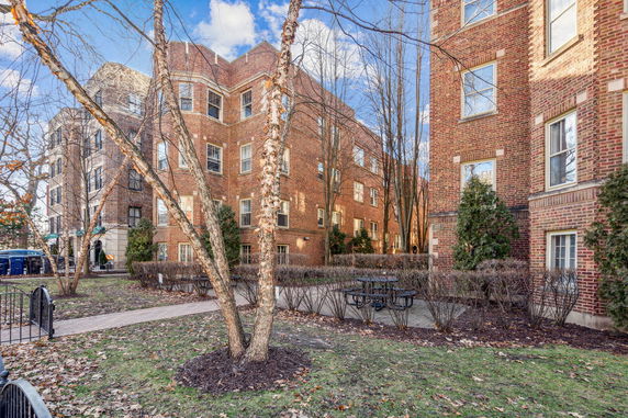 Front view of a multi-story brick apartment building with rectangular windows.