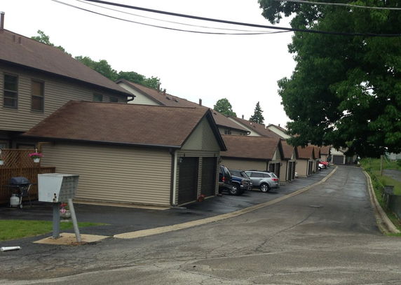Outdoor parking area in front of a row of attached garages.