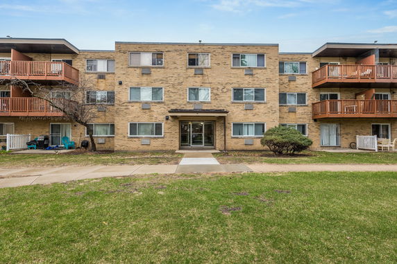 Front view of a three-story brick apartment building with multiple balconies.