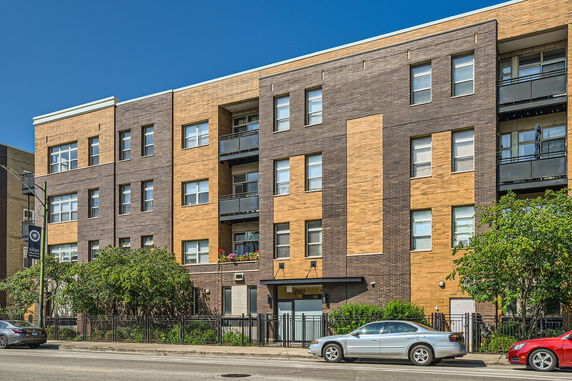 Front view of a multi-story brick apartment building with balconies.