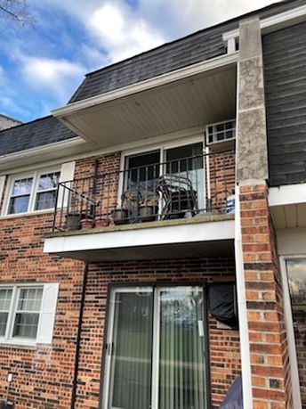 Front view of a multi-story brick building with a balcony.