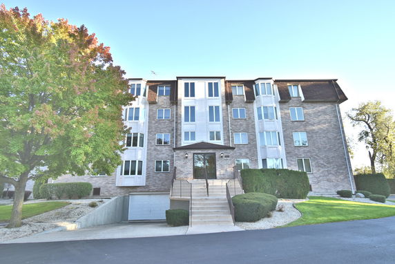 Front view of a multi-story apartment building with large windows and a central entrance.