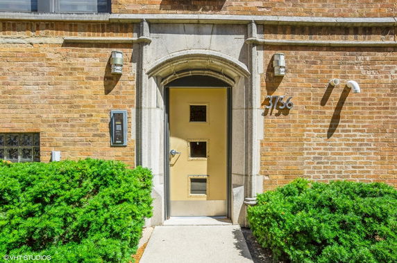 Front view of a building entrance with a rectangular door and brick walls.