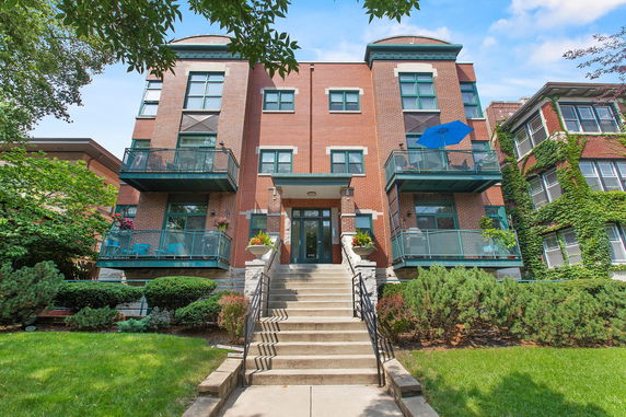 Front view of a multi-story brick apartment building with balconies.