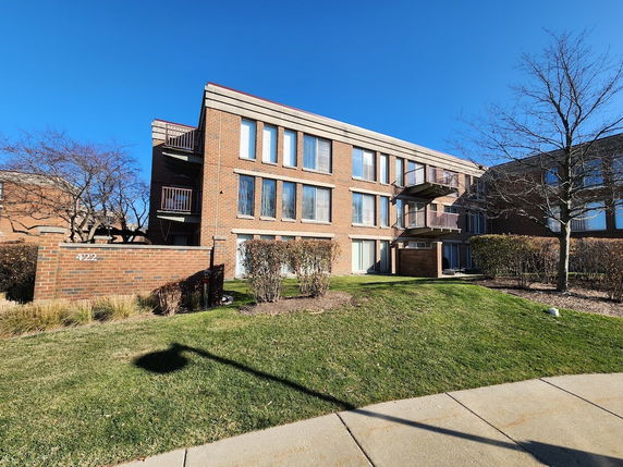 Front view of a multi-story brick building with large windows and balconies.
