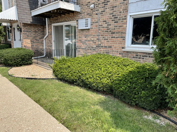Front view of a brick apartment building with sliding glass door and window.
