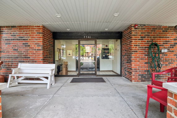 Front entrance of a brick building with glass doors and benches.