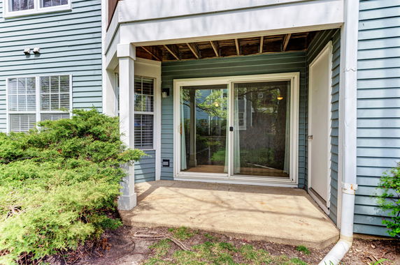 Front view of a house with a patio and sliding glass door.
