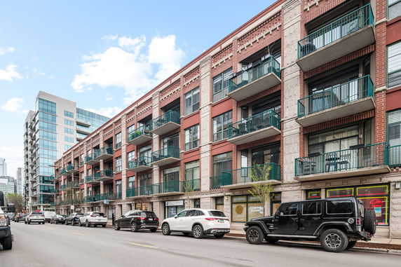 Front view of a multi-story brick apartment building with balconies.