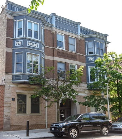 Front view of a three-story building with decorative blue and brick exterior.