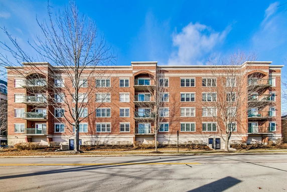 Front view of a multi-story brick residential building with balconies.