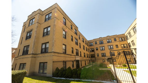 Front view of a multi-story apartment building with a gated entrance.